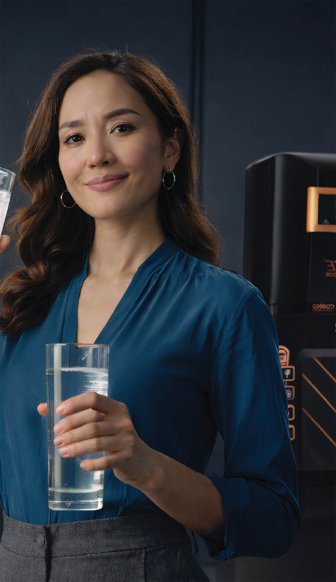A woman holding a glass of purified water beside a Beckon purifier